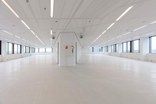 Licht en ruim leeg kantoorpand aan de Vliegend Hertlaan met grote raampartijen en witte vloer.